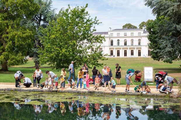 Family day out with mini beast safari hunt at Gunnersbury Park with view of museum and horseshoe pond